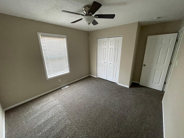 unfurnished bedroom with ceiling fan, baseboards, a closet, a textured ceiling, and dark colored carpet