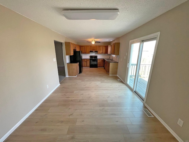 kitchen featuring visible vents, light wood-style flooring, under cabinet range hood, freestanding refrigerator, and stove