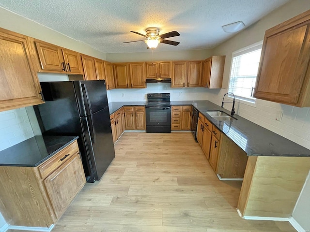 kitchen with under cabinet range hood, light wood-style floors, black appliances, a ceiling fan, and a sink