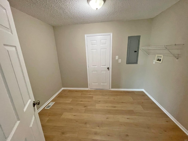 clothes washing area with visible vents, light wood-type flooring, electric panel, laundry area, and hookup for a washing machine