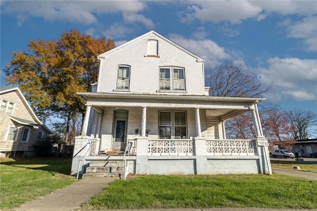 view of front facade featuring brick siding, a porch, and a front yard