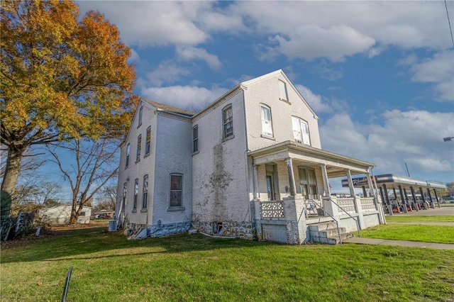 view of front facade featuring a front yard, brick siding, and covered porch