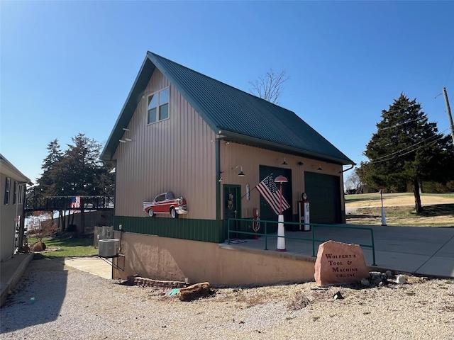 exterior space with central AC unit, metal roof, and a garage