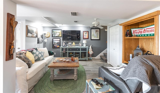 living area with stairs, baseboards, visible vents, a ceiling fan, and wood finished floors