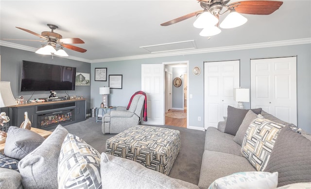 living area with a ceiling fan, carpet, attic access, and ornamental molding