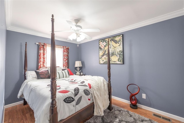 bedroom featuring baseboards, visible vents, crown molding, and wood finished floors