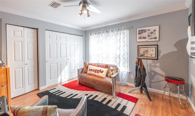 sitting room with crown molding, baseboards, ceiling fan, visible vents, and wood finished floors