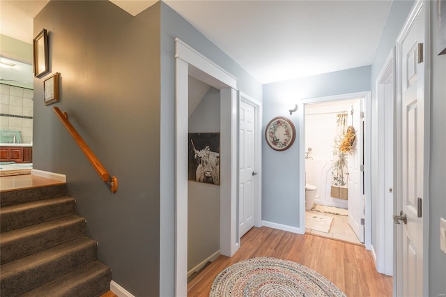 hall featuring baseboards, light wood-style flooring, and stairway