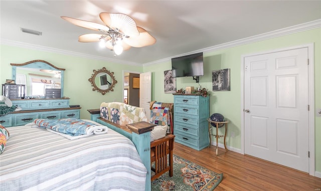 bedroom with wood finished floors, ornamental molding, baseboards, and visible vents