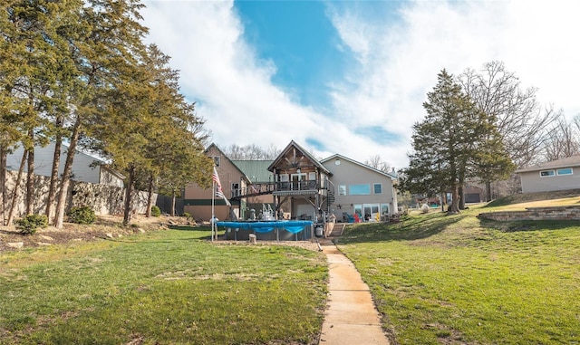 back of property with a covered pool, stairs, a deck, and a yard