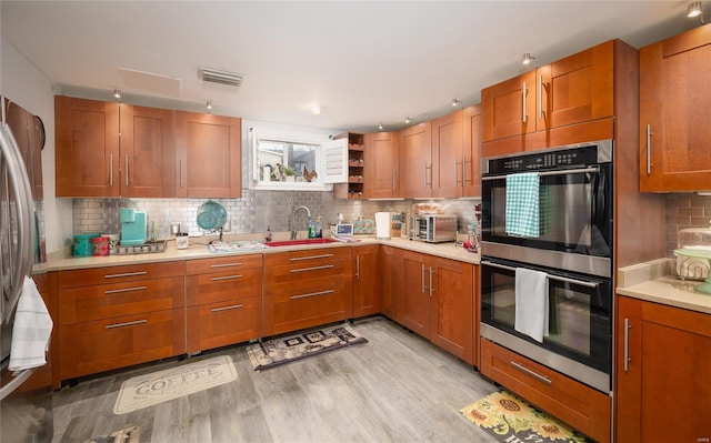 kitchen featuring light countertops, visible vents, brown cabinets, appliances with stainless steel finishes, and a sink