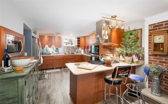 kitchen featuring decorative backsplash, light countertops, a peninsula, brown cabinets, and open shelves