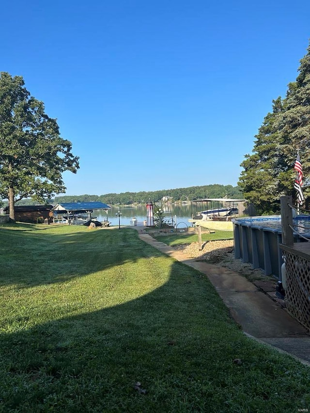 view of yard with a water view, an outdoor pool, and a boat dock
