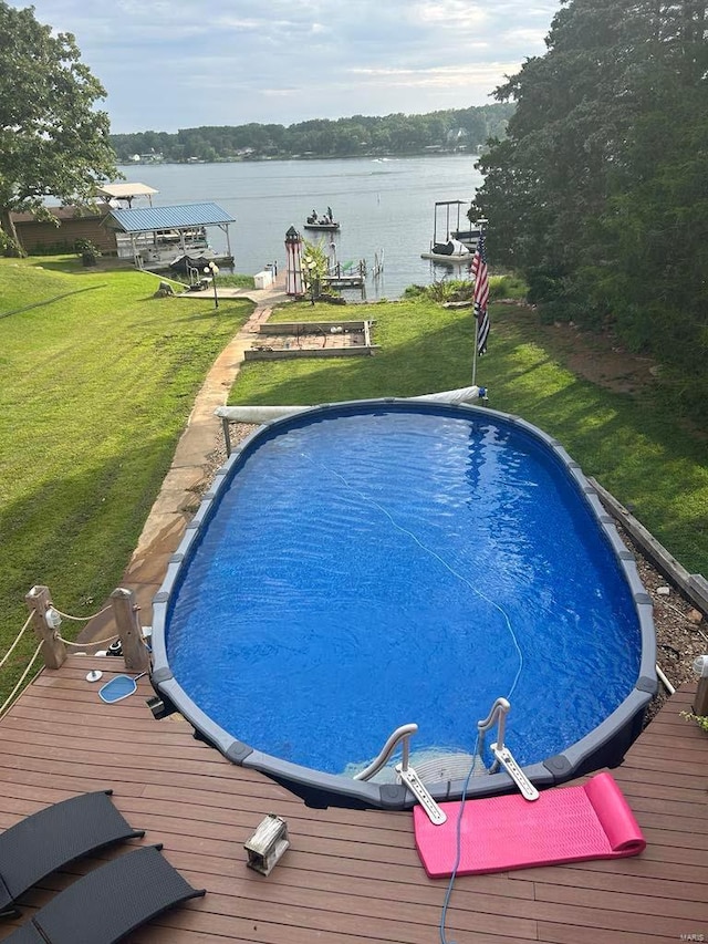 view of swimming pool featuring a lawn, a water view, and a boat dock