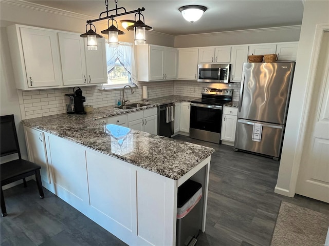 kitchen featuring a sink, appliances with stainless steel finishes, a peninsula, and ornamental molding