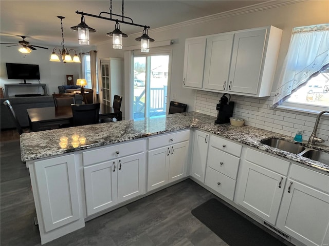 kitchen featuring a sink, a peninsula, crown molding, and a healthy amount of sunlight