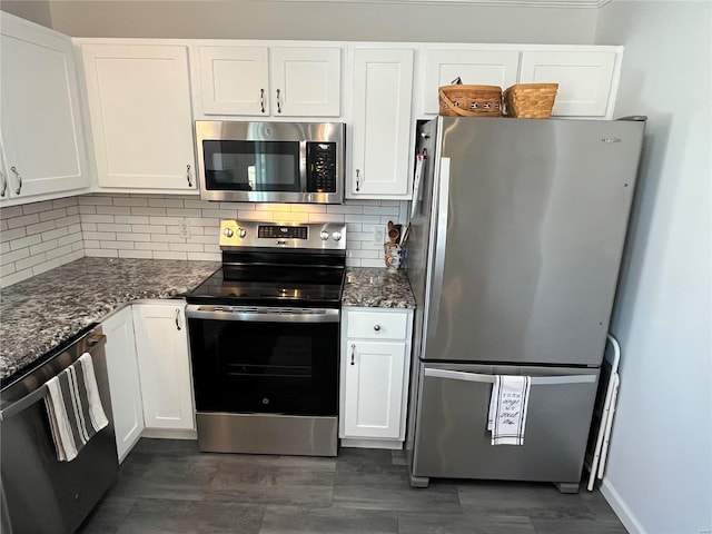 kitchen with decorative backsplash, white cabinetry, stainless steel appliances, and dark stone counters