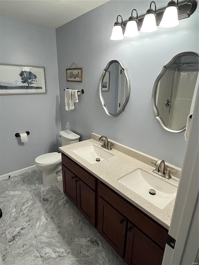 bathroom featuring double vanity, toilet, marble finish floor, and a sink