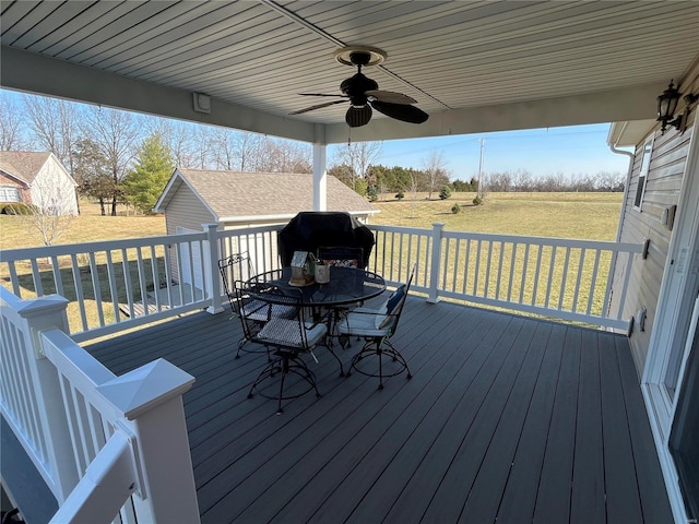 wooden deck featuring a yard, a grill, outdoor dining area, and a ceiling fan