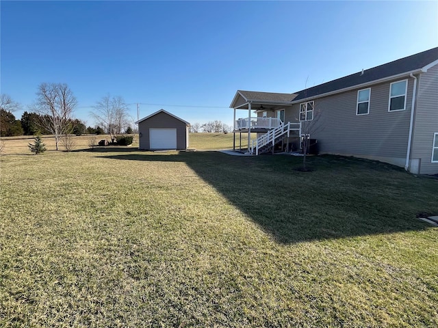 view of yard with driveway, an outdoor structure, a garage, ceiling fan, and stairs