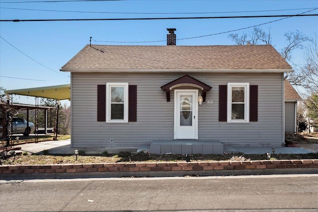 bungalow featuring roof with shingles and a chimney