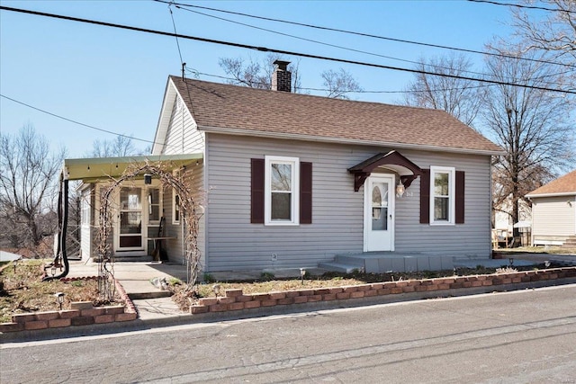 bungalow with a shingled roof and a chimney