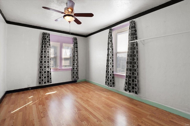 spare room featuring ceiling fan, crown molding, baseboards, and wood finished floors