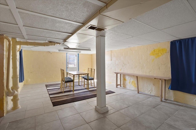 basement featuring tile patterned floors, visible vents, and a paneled ceiling