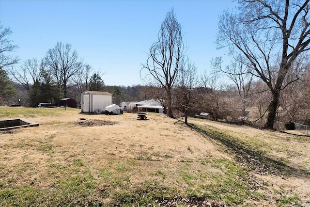 view of yard featuring a fire pit, an outbuilding, and a shed