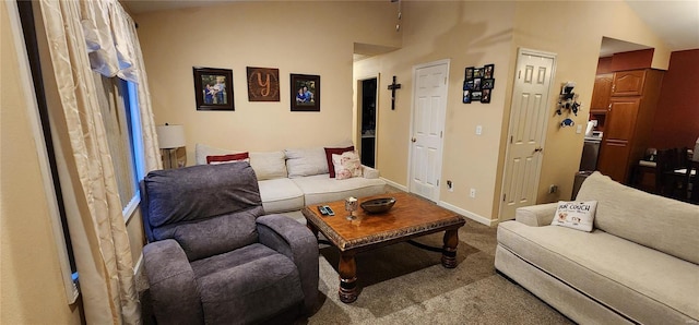 carpeted living area with baseboards and vaulted ceiling