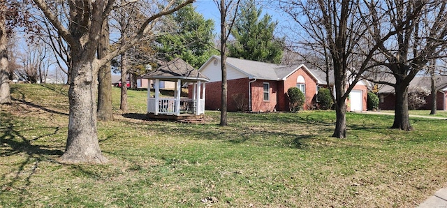 view of front facade featuring a gazebo, a garage, brick siding, and a front yard