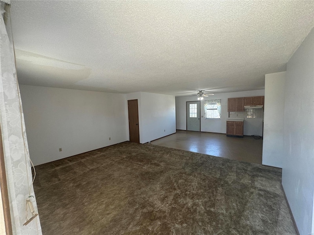 unfurnished living room featuring a textured ceiling, ceiling fan, and dark carpet