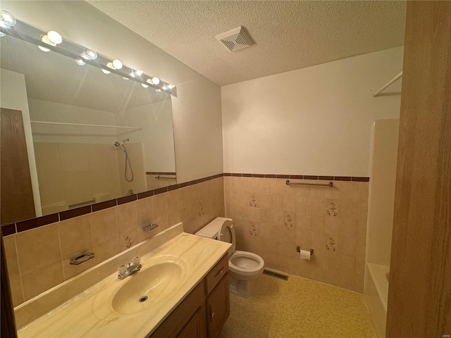 full bathroom featuring visible vents, a textured ceiling, a wainscoted wall, and toilet