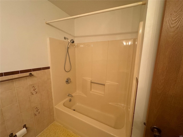 bathroom featuring tub / shower combination, tile walls, and wainscoting