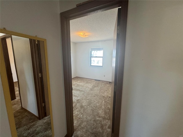 hall featuring a textured ceiling and carpet floors