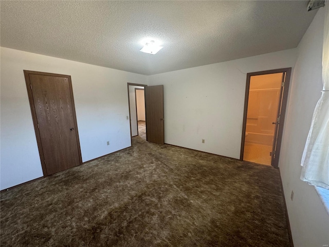 unfurnished bedroom featuring ensuite bath, carpet, a closet, and a textured ceiling