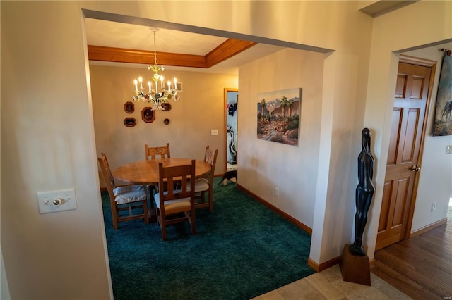 carpeted dining room featuring a chandelier, baseboards, and ornamental molding