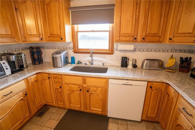 kitchen featuring dishwasher, visible vents, a sink, and backsplash