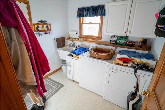 clothes washing area with cabinet space, washing machine and clothes dryer, a sink, and light floors