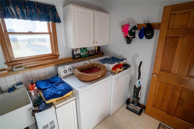 clothes washing area with separate washer and dryer and cabinet space