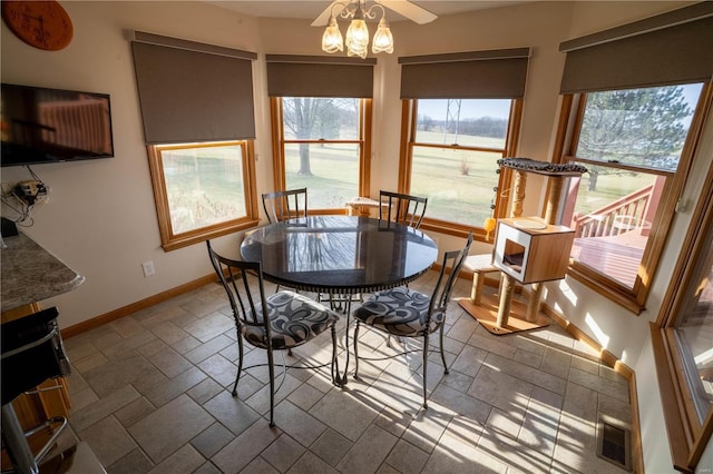 dining area featuring stone tile flooring, baseboards, visible vents, and a wealth of natural light