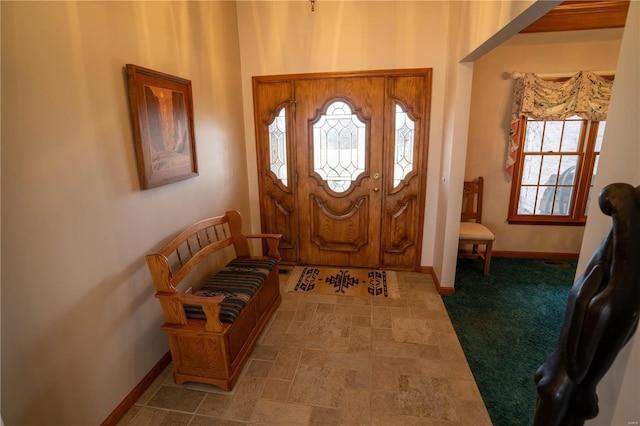 foyer featuring baseboards and stone finish floor