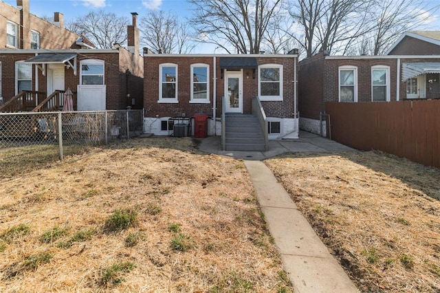 view of front facade with brick siding, central AC unit, fence private yard, and entry steps