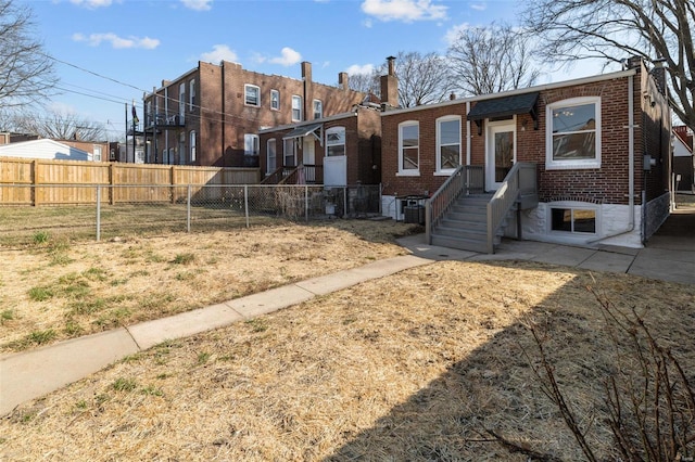 view of front of house featuring brick siding, central AC unit, a chimney, and fence