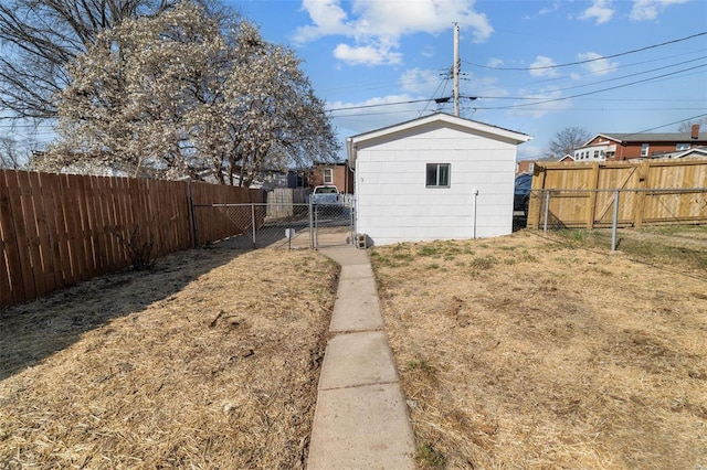 view of yard with an outdoor structure, a gate, and a fenced backyard