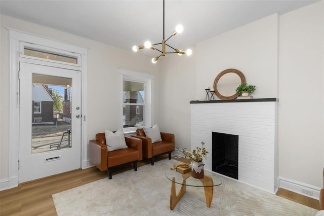 sitting room featuring a fireplace, an inviting chandelier, wood finished floors, and baseboards