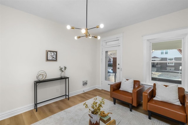 sitting room with baseboards, an inviting chandelier, and wood finished floors