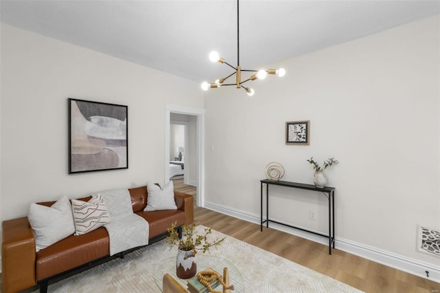 living area with visible vents, baseboards, an inviting chandelier, and wood finished floors