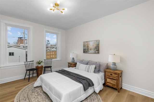 bedroom with baseboards, light wood-style floors, and an inviting chandelier