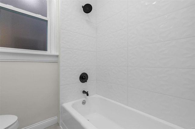 bathroom featuring shower / washtub combination, toilet, and baseboards